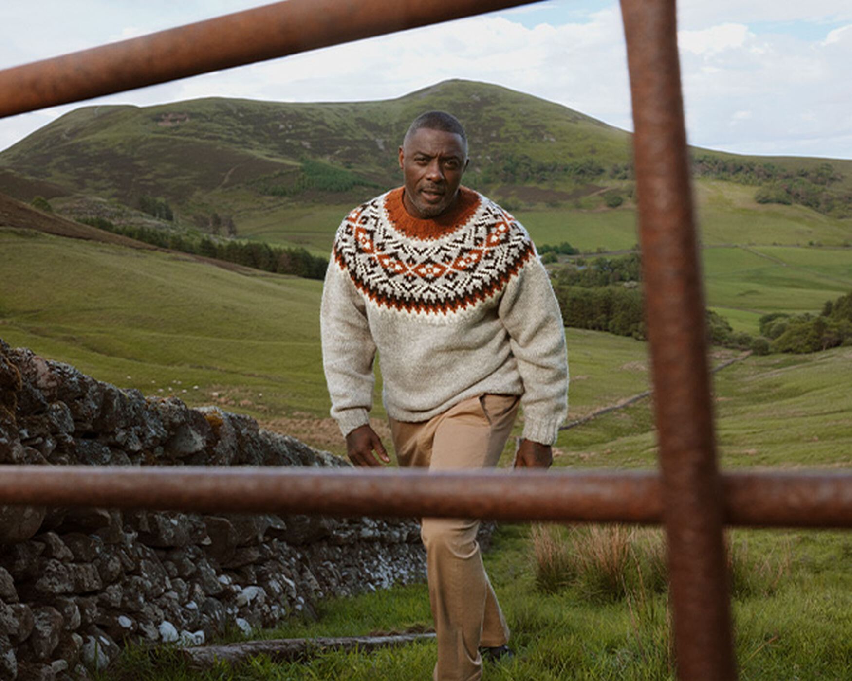 Man in a Fair Isle knit walking through hill country